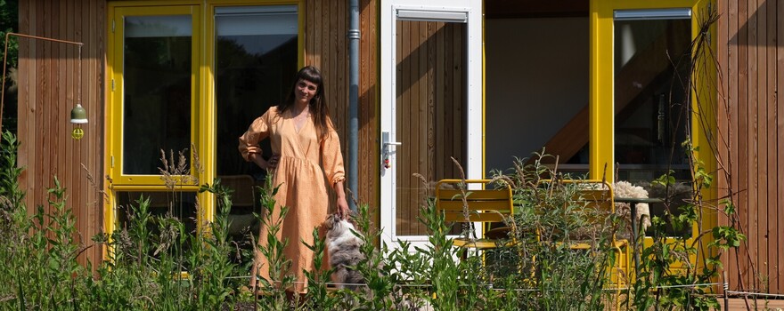 Een vrouw staat met haar hond voor haar tiny house